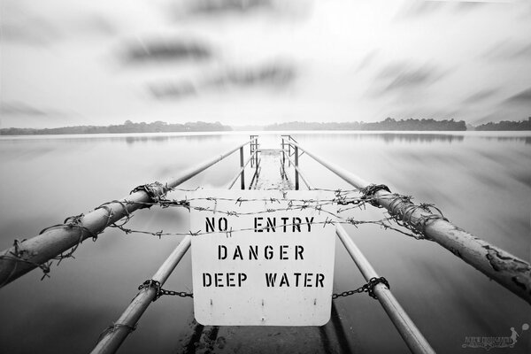 Black and white picture of a lake with a sign