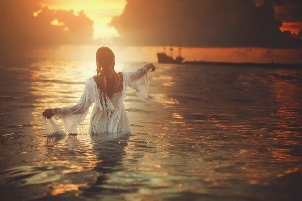 A girl in the water waves to the ship