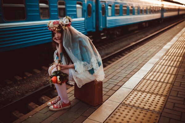 Una novia con una maleta en la plataforma y un tren tarde