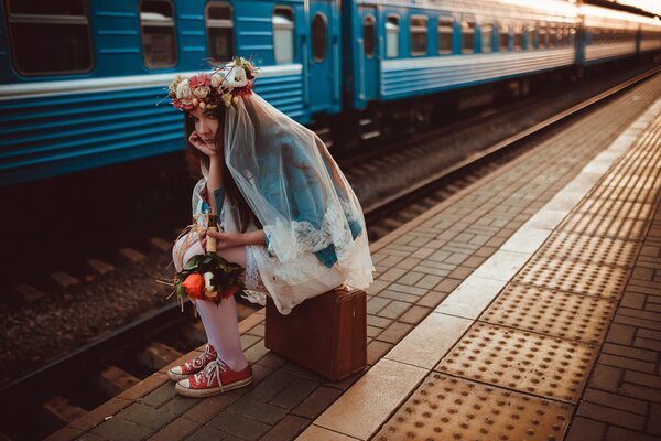 Panna młoda z walizką na peronie i spóźnionym pociągiem