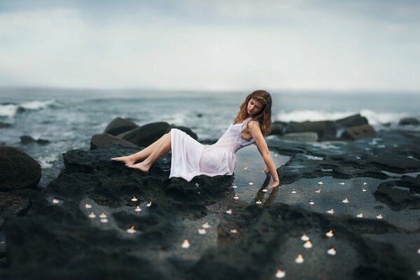 Chica sentada en las rocas cerca del mar