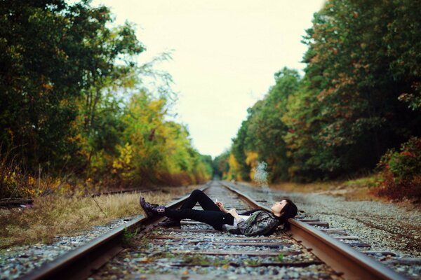 La jeune fille se trouve et fume sur les rails