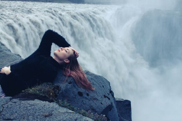 Fille en noir se trouve sur le bord de la cascade