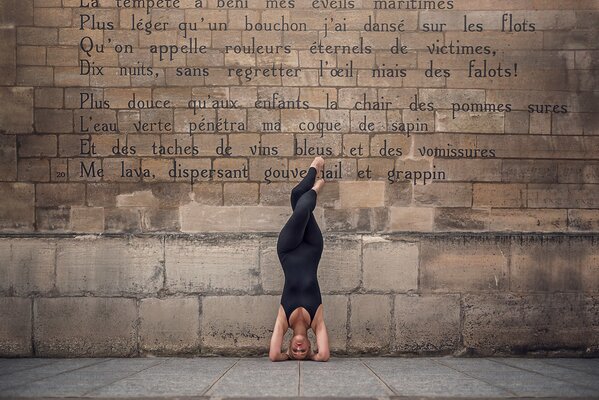 A ballerina in a pose against a wall with poems