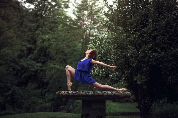 Chica en vestido azul hace ejercicio en el bosque