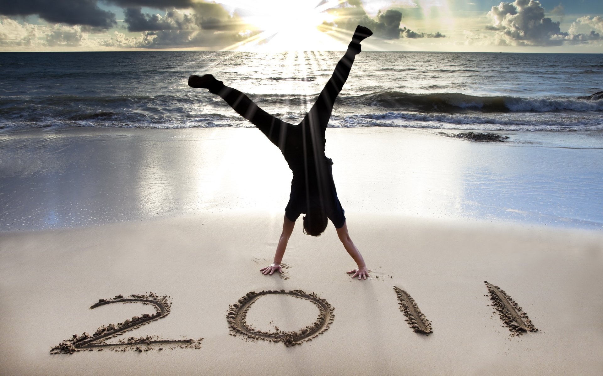 beach sand sea shore numbers year man hands horizon sky clouds sun light ray