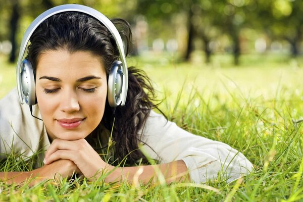 A girl resting on the grass and listening to music