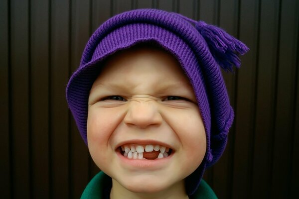 Chłopiec w fioletowej czapce i bez zębów
