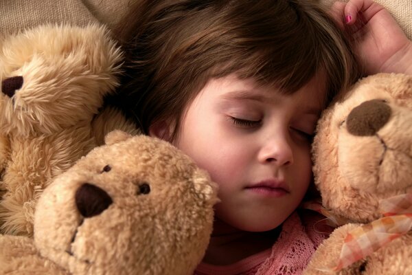 A little girl sleeping sweetly surrounded by her favorite toys, teddy bears