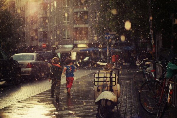 Children run along the sidewalk in the rain