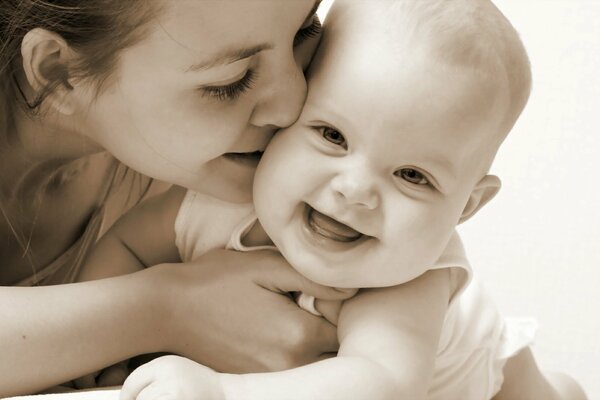 Mama całuje uśmiechnięte dziecko