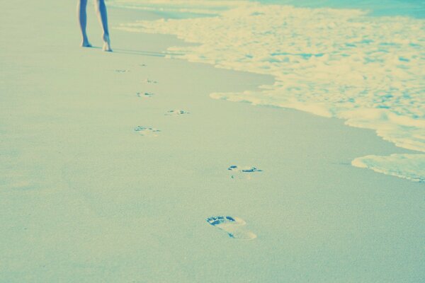 A girl walking on the sand leaving footprints