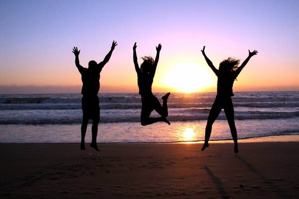 Three girls taking pictures at sunset