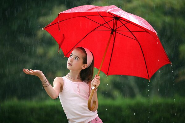 Niña con paraguas rojo en clima lluvioso