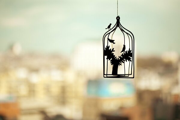 Decoración de un pájaro en una jaula contra el fondo de la ciudad