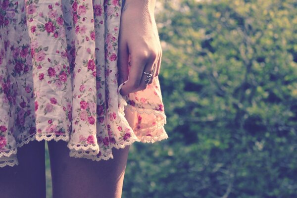 The hem of a girl s dress against a background of trees