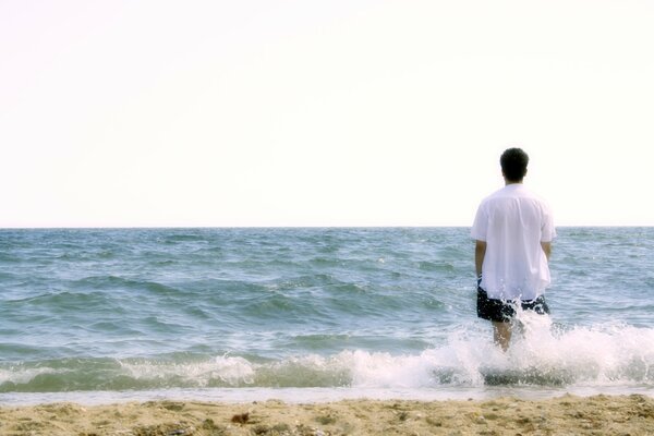 Hombre en la orilla del mar en el rocío de las olas