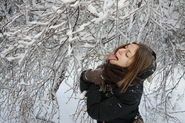 The girl catches the snow with her tongue