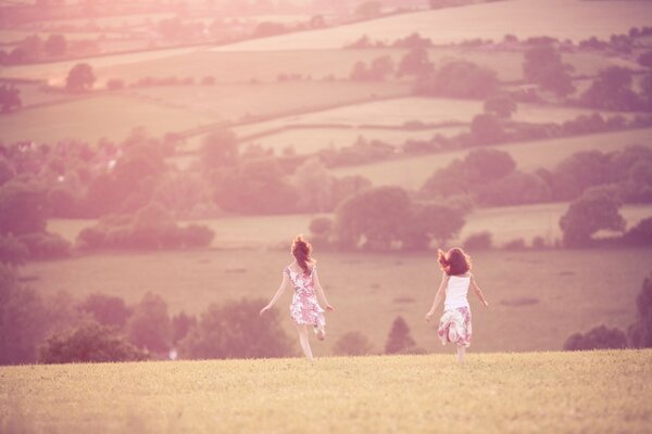 Two girls are running through the fields