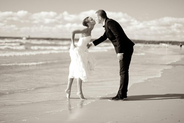 La novia y el novio se besan junto al mar