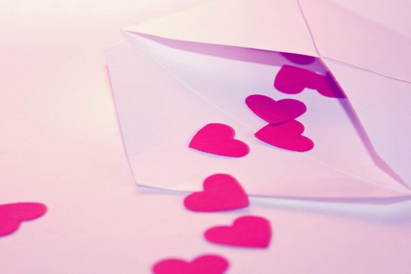 A love letter in an envelope with a scattering of pink hearts