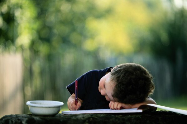El niño escribe acostado con un lápiz