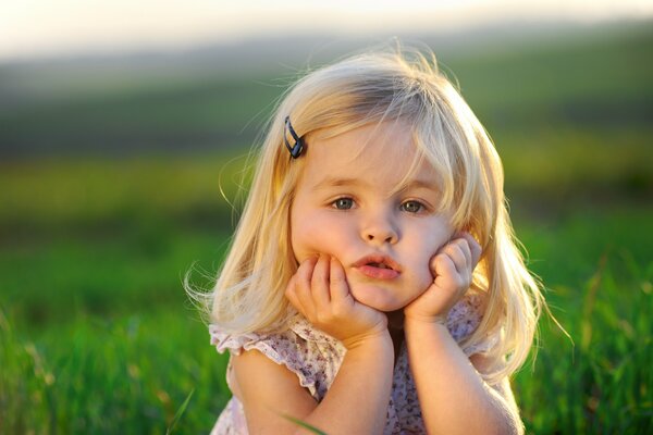 Pensive baby and green grass