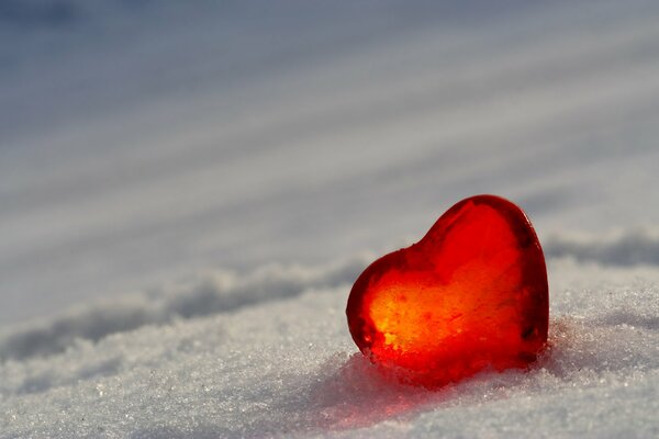 Piccolo cuore di vetro rosso sulla neve bianca