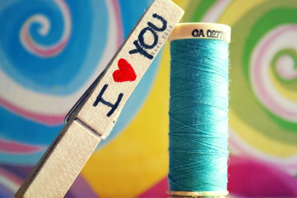 Multicolored threads and a clothespin with the inscription I love you