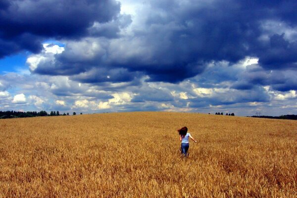 A girl running across a field into the sunset