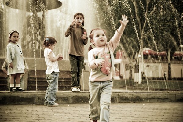 Small children walk in the park by the fountain