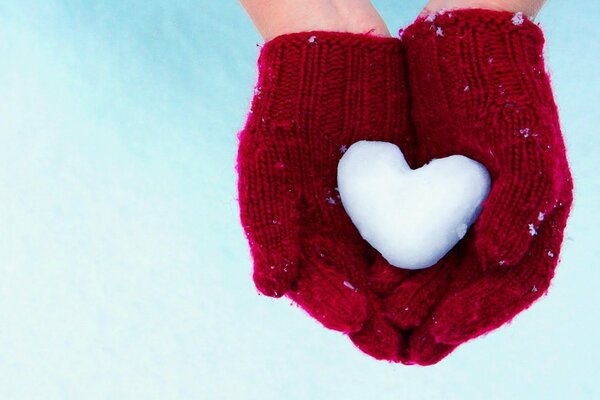 A heart made of snow in the hands of a man