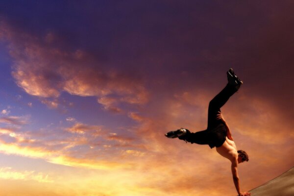 Hombre bailando en el fondo del cielo al atardecer