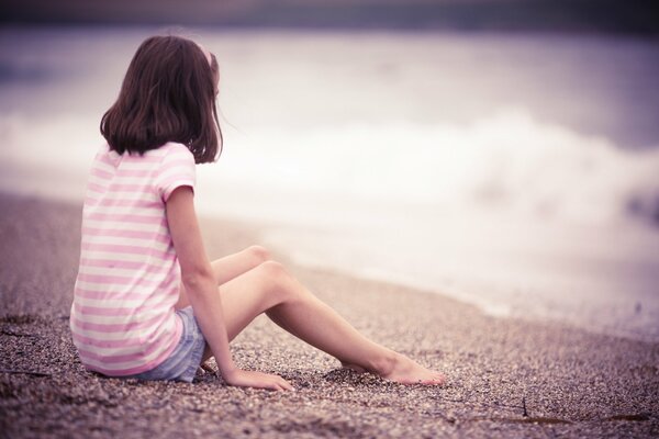 The girl is sitting on the seashore