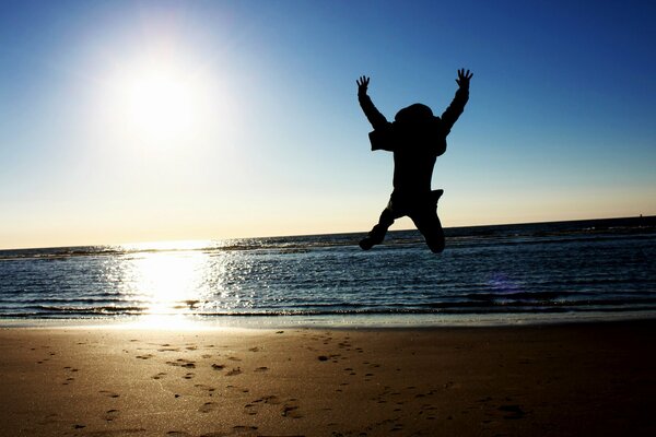 Guy jumps on the beach by the sea