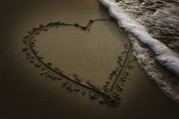 A painted heart on the sand with waves