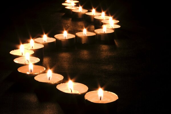 Pływające świece skomponowane w kształcie fali płoną w ciemności