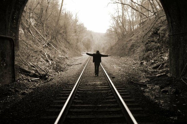 A girl on the rails against the background of the tunnel. Black and white