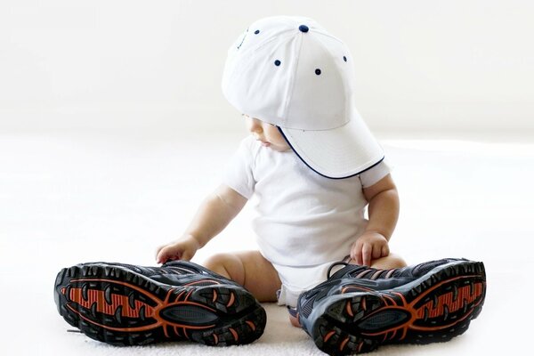 Ragazzino in grandi scarpe da ginnastica e berretto bianco