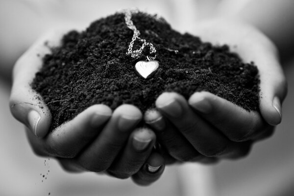 Hands holding the ground with a heart pendant