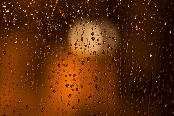 Der Regen hat Tropfen auf dem Glas des Abendfensters hinterlassen