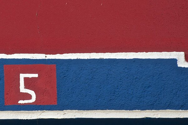 Pared roja y azul con el número cinco en la mitad azul