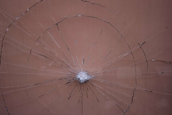 Разбитое стекло с застрявшим камнем по середине