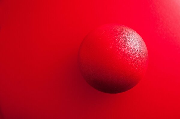 Rote Kugel auf hellem scharlachrotem Hintergrund