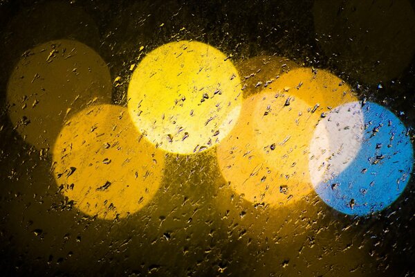 Six grands cercles multicolores sur un verre trempé de pluie