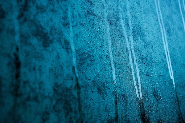 Wassertropfen auf beschlagenem blauem Glas