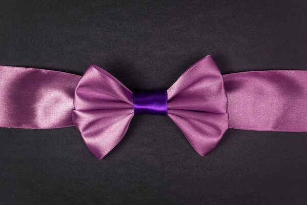 Wide pink ribbon with a bow on a gray background