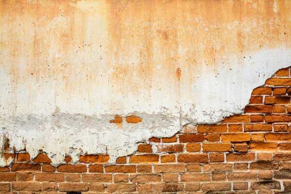 Vieux mur de briques recouvert de plâtre nerveux