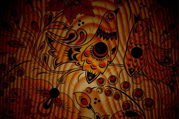 On a wooden plate there is an image of berries and patterns . Two birds are sitting on the branches . Reaching for the berry