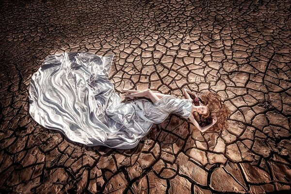 Mädchen in einem schicken Kleid auf dem Hintergrund der Erde Dürre und Risse